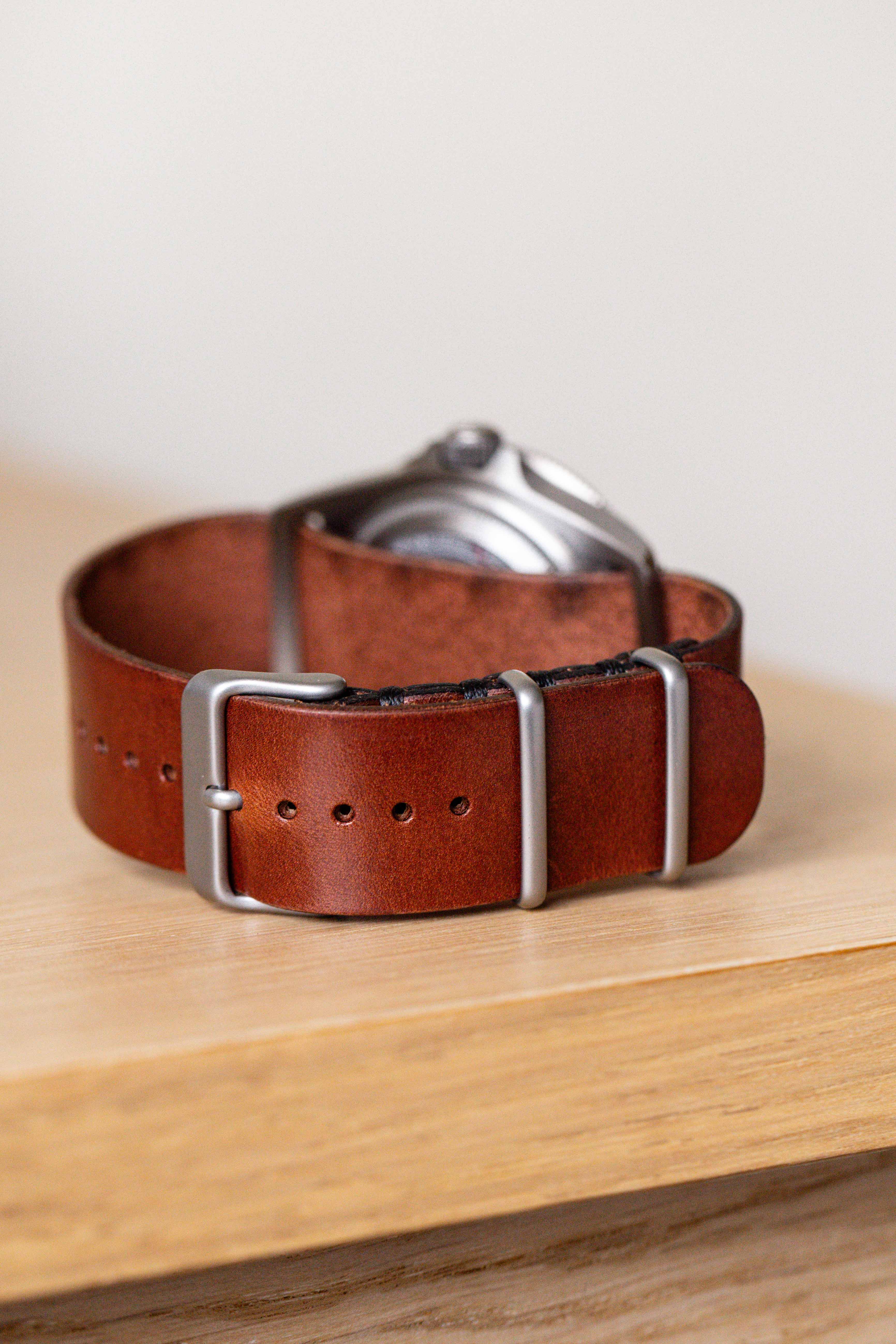steel pin buckle leather watch strap independent watch close-up macro on weathered wood natural light